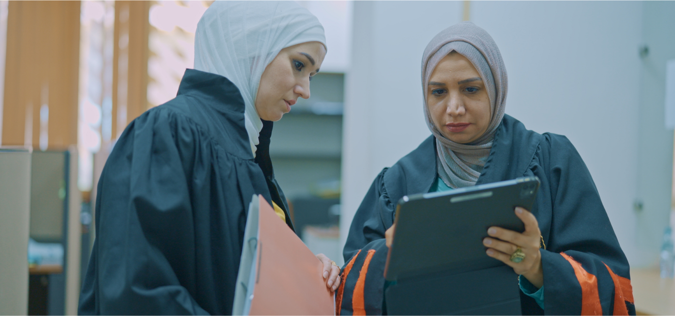 Two female prosecutors deliberating on an electronic file provided through Mizan ahead of a court hearing.